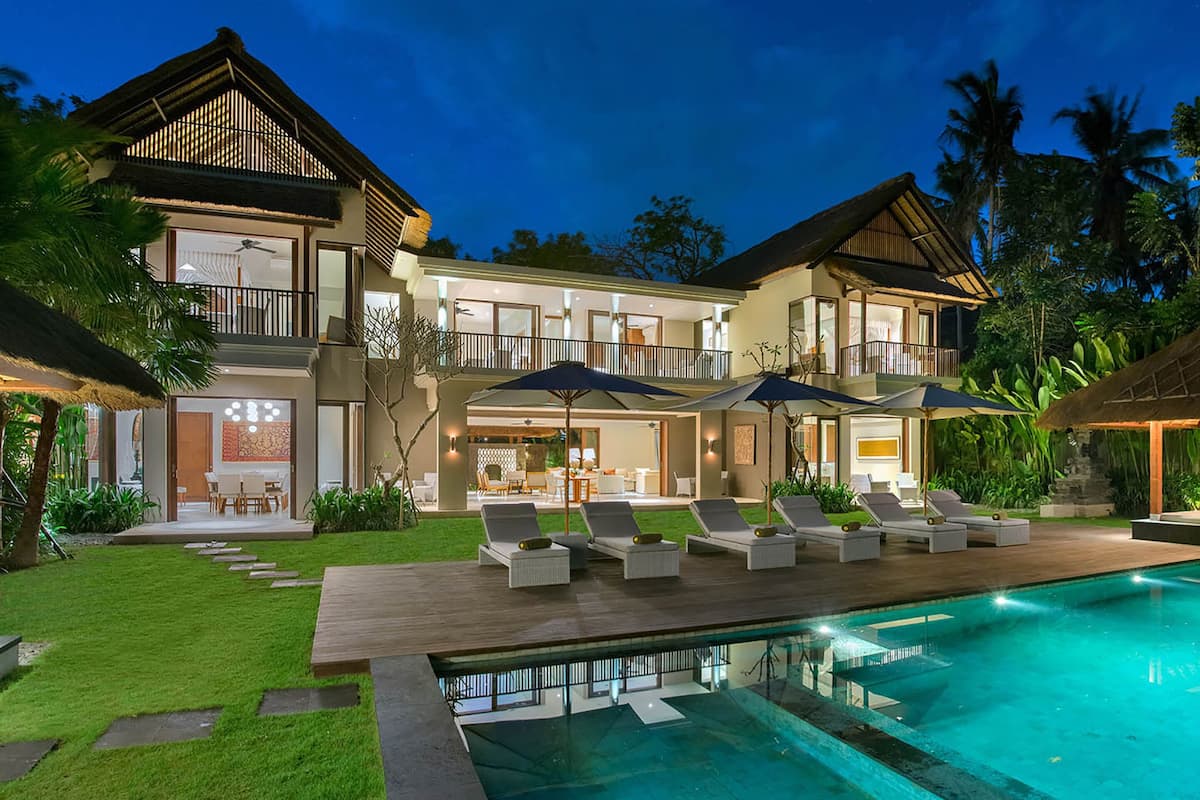 A two-story house with a swimming pool, outdoor seating, and a well-maintained garden.