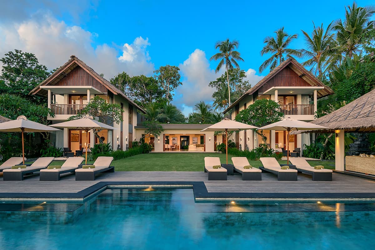 A resort with a swimming pool, lounge chairs, and a well-maintained garden.