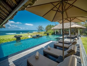 A poolside area with lounge chairs and a view of the ocean. - Seseh Beach Villas (Cemagi)