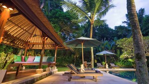 A poolside area with lounge chairs, umbrellas, and a thatched-roof structure. - Villa Alamanda (Ubud)