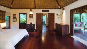 A spacious bedroom with a large bed, wooden furniture, and a view of lush greenery outside. - Villa Alamanda (Ubud)