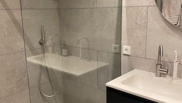 Een bad/douchecombinatie, een haardroger, handdoeken, toiletpapier