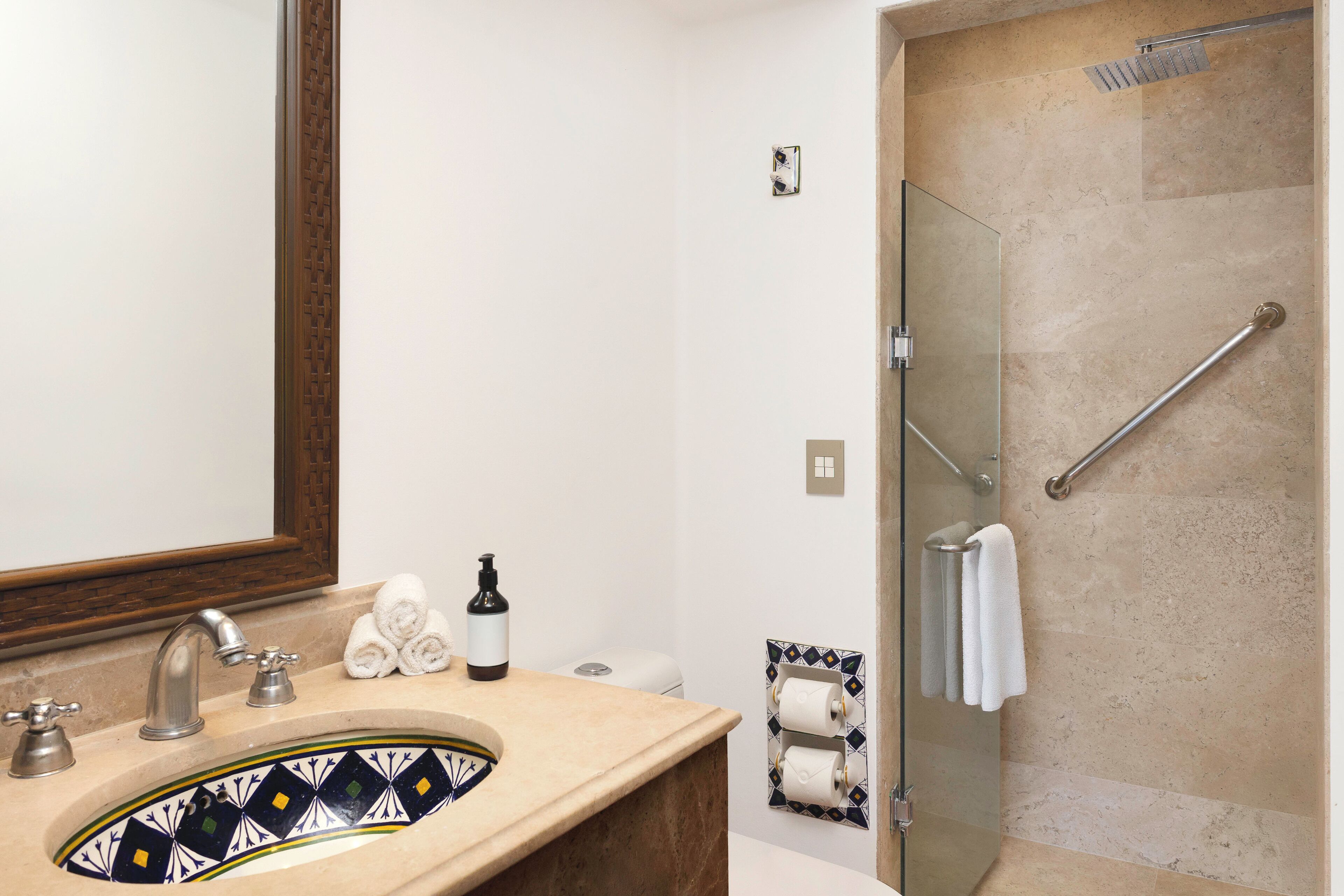 A bathroom with a sink, mirror, towel rack, and a glass shower enclosure.