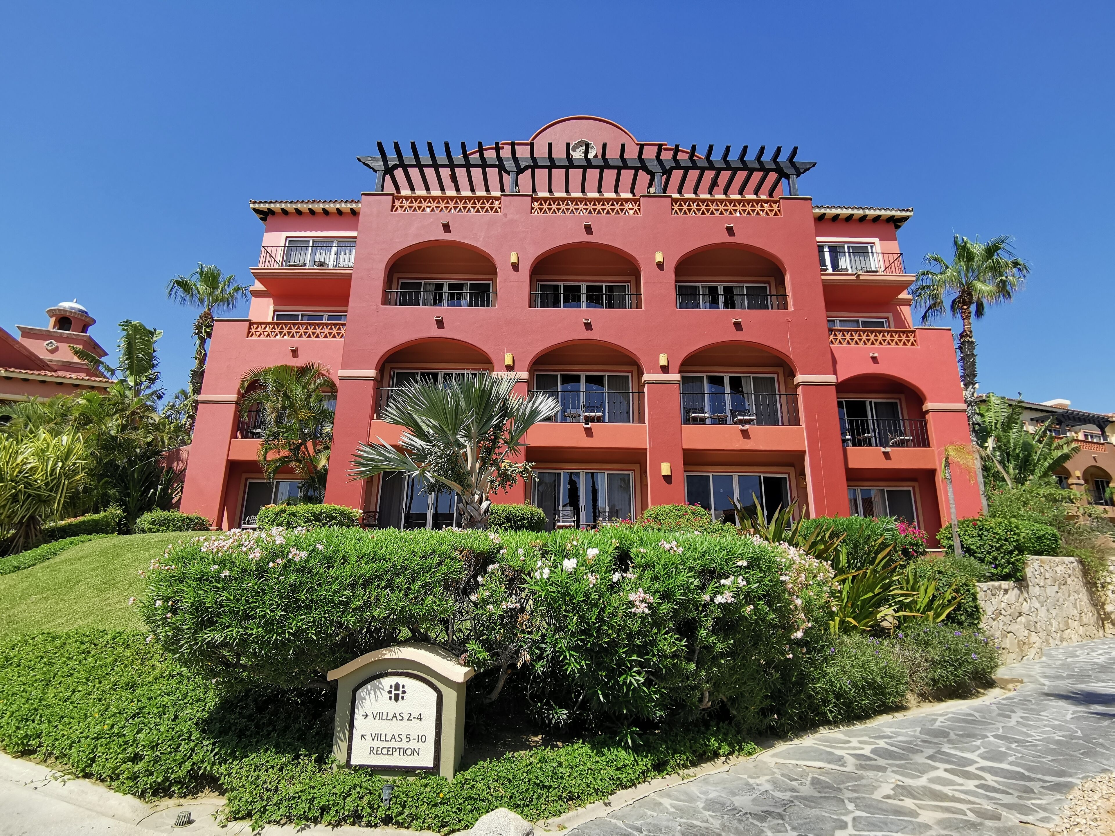 Un hotel de varios pisos con fachada roja, ventanas en arco y una entrada central.