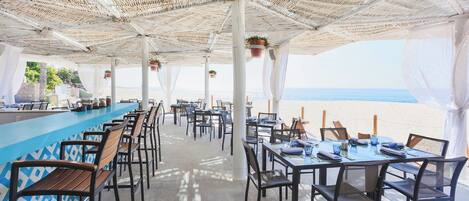 Un espace de restauration en plein air avec des tables et des chaises, un bar et une vue sur la plage.