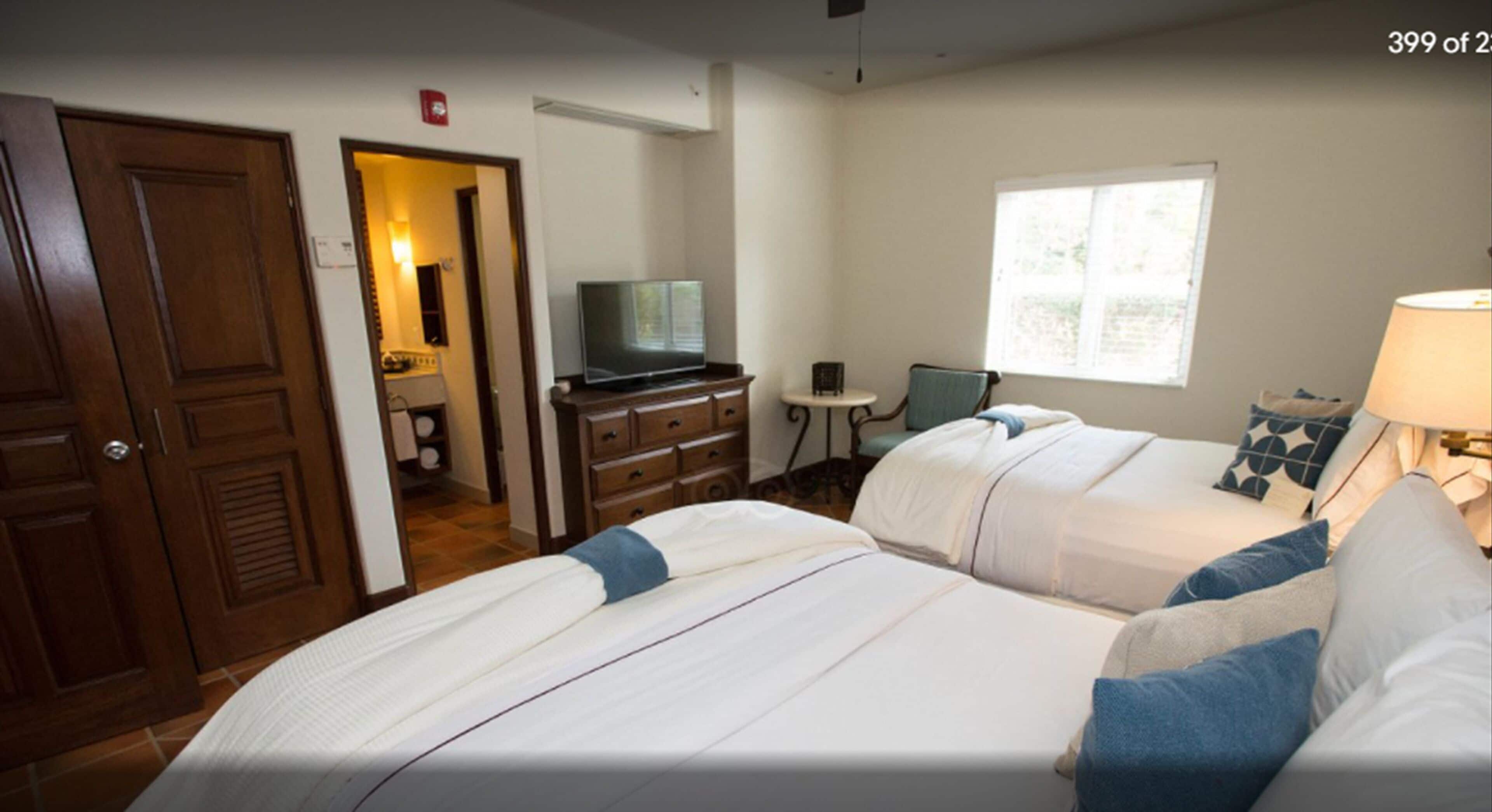 Une chambre d’hôtel avec deux lits, une télévision, un bureau et une fenêtre.