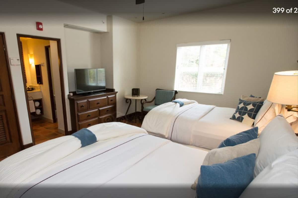 Une chambre d ’hôtel avec deux lits, une télévision, un bureau et une fenêtre.