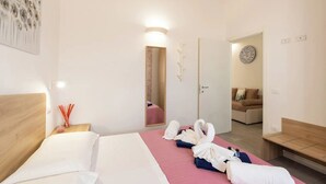 A hotel room with a bed, a bench, a door, and a wall clock. - Gioberta Holiday Homes, Cipollazzo Villa (Menfi)