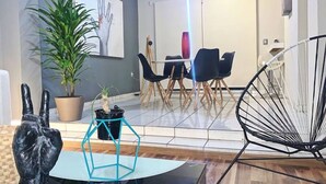 A modern living room with a white sofa, a black chair, a blue geometric coffee table, and a potted plant. - Charming House Rental in Zapopan, Mexico - Your Private Oasis (Zapopan)