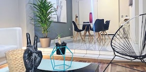 A modern living room with a white sofa, a black chair, a blue geometric table, and a potted plant. - Casa Valeria, ¡a Sólo 10 Minutos De Andares! (Zapopan)