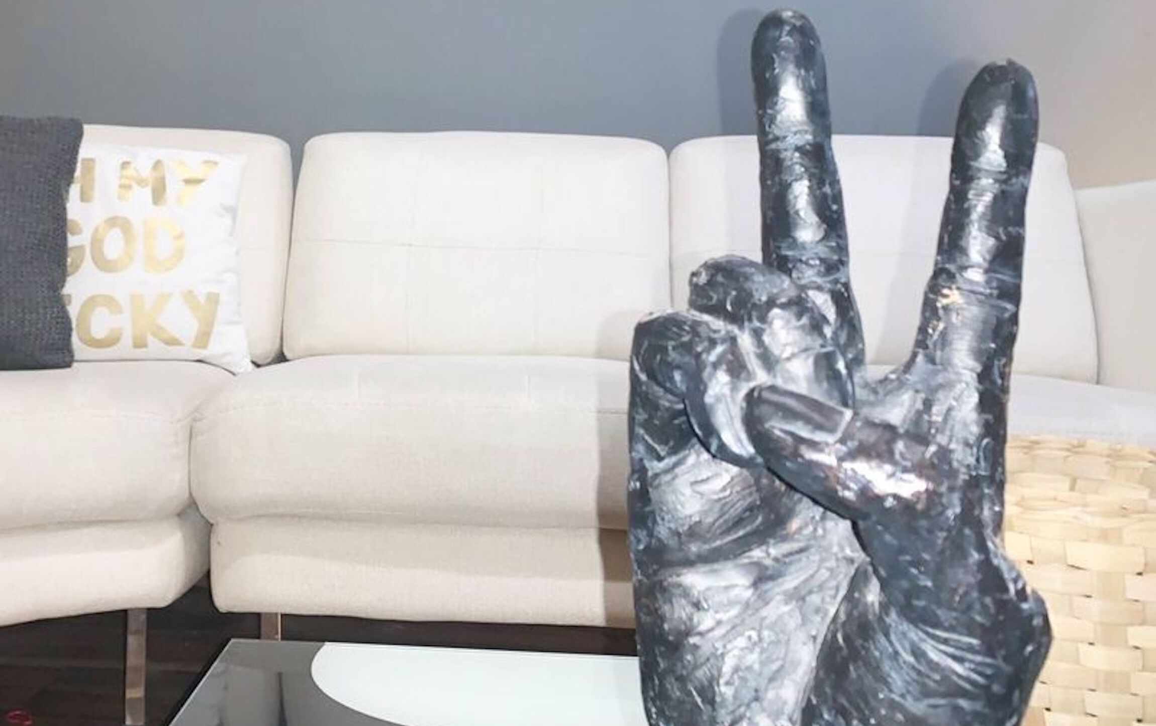 A white sofa with a cushion that has "MY GOD ISCKY" printed on it.