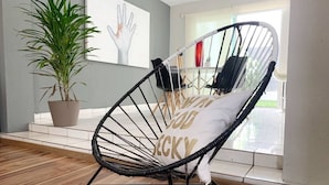 A room with a wicker chair, a potted plant, and a view of the outdoors. - Charming House Rental in Zapopan, Mexico - Your Private Oasis (Zapopan)