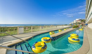 A pool with yellow and blue inflatable rings, a lifeguard stand, and a view of the ocean. - Westgate Myrtle Beach Oceanfront 828-94 (Myrtle Beach)
