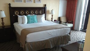 A hotel room with a large bed, two bedside tables, a chair, and a window with curtains. - Westgate Myrtle Beach Oceanfront 828-94 (Myrtle Beach)