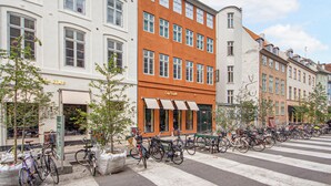 Une vue de rue avec une rangée de vélos garés, un passage piéton et des bâtiments dotés d’auvents.
