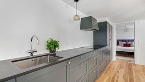 Une cuisine moderne dotée d’un grand îlot central, d’un évier intégré et d’un luminaire suspendu.