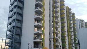 Un immeuble résidentiel à plusieurs étages, doté de balcons, d’un terrain de jeux et situé devant une rue.