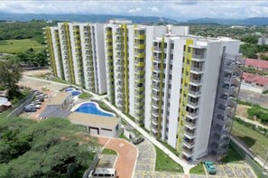 A high-rise residential building with multiple balconies, a swimming pool, and a parking area. - Total Spacio Relax in Cundinamarca (Tocaima)