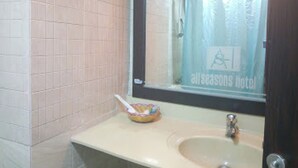 A bathroom with a sink, mirror, and a window with a curtain. - Room-all Seasons Hotel - Business Suite (Owerri)