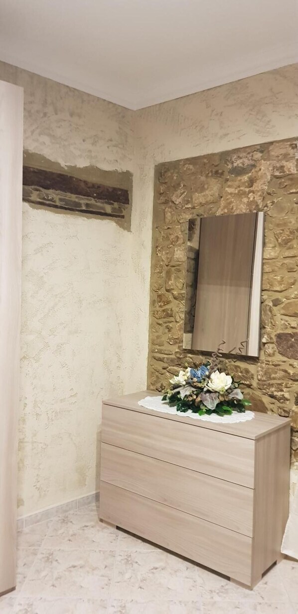 Un baño con pared de piedra, tocador de madera y espejo.