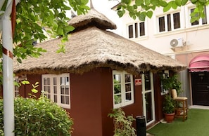 A small building with a thatched roof, a door, and windows. - Room-auris Court - Guest Room (Abuja)