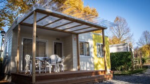 A single-story house with a covered porch, a table with chairs, and a gravel driveway. - Cottage Eco House - Ideal for 4 People (Alba)