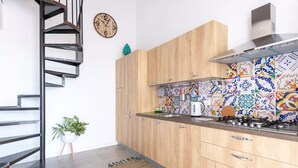 A modern kitchen with wooden cabinets, a gas stove, and colorful backsplash tiles.