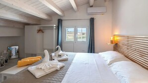 A hotel room with a large bed, a wooden headboard, a window with curtains, and a view of the landscape.