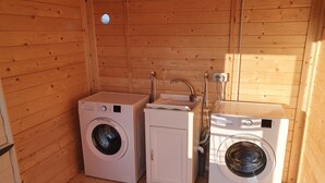 Une petite buanderie avec trois machines à laver, un évier et des murs en bois.