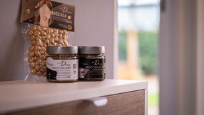 Zwei Gläser Nocciola auf einer Holzoberfläche, im Hintergrund eine Karte und eine Tüte Nüsse.