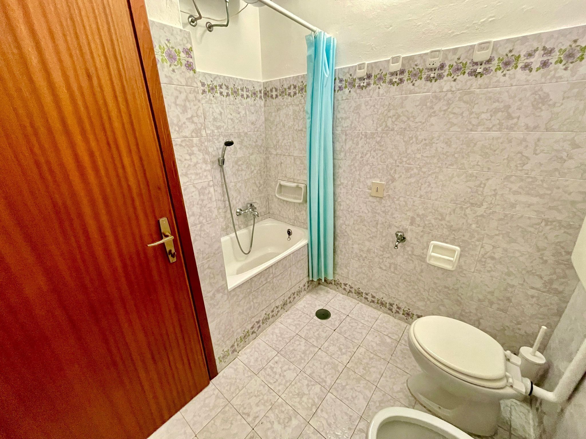 A bathroom with a bathtub, toilet, and shower curtain.