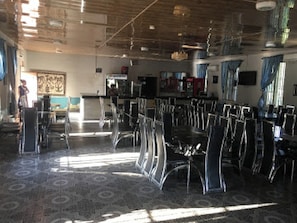 A spacious dining area with high tables and chairs, a bar area, and a view of the outdoors.