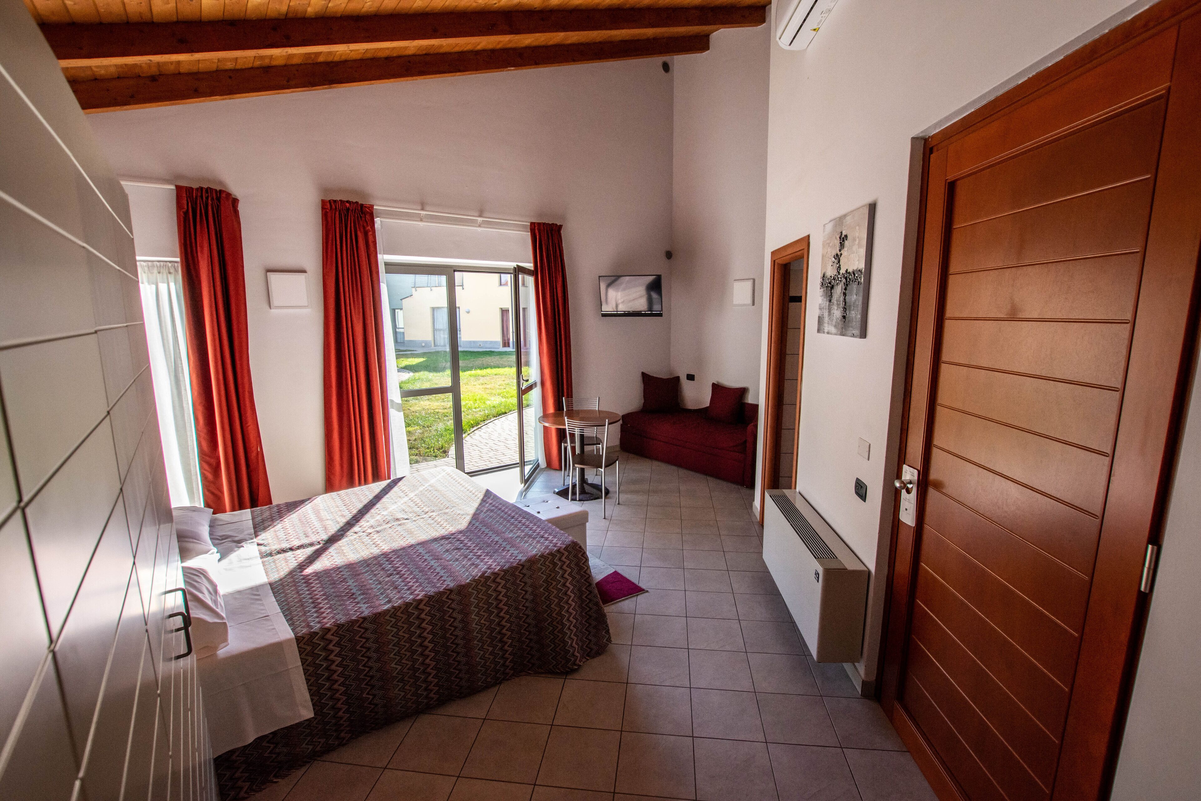 Ein Schlafzimmer mit einem Bett, einem Schreibtisch und Blick ins Freie.