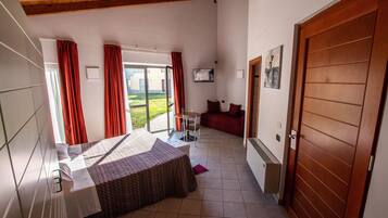 Ein Schlafzimmer mit einem Bett, einem Schreibtisch und Blick ins Freie.