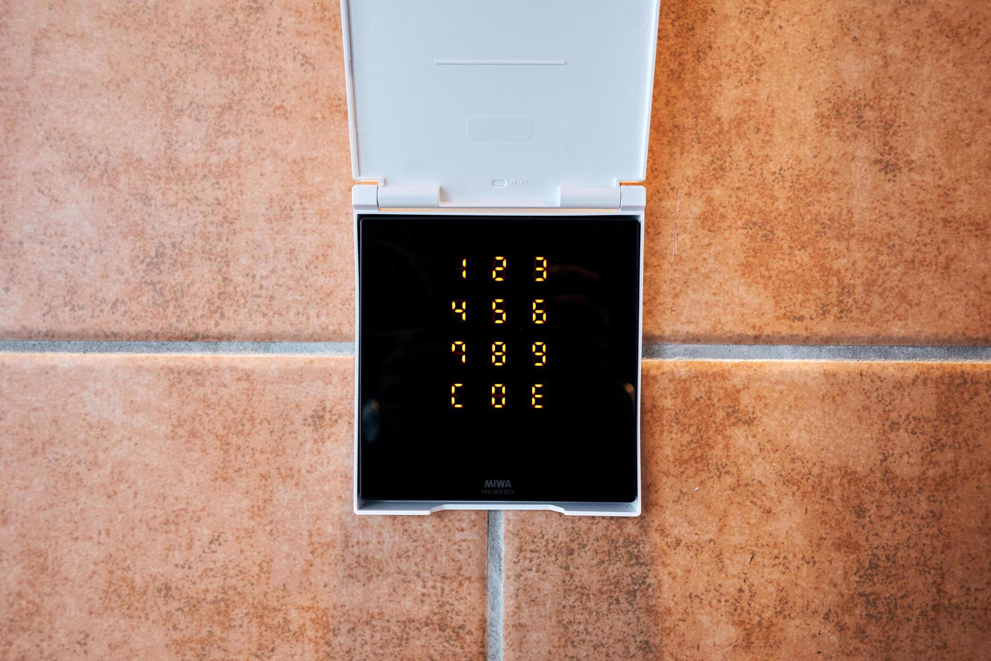 A digital keypad lock on a tiled wall.
