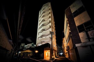 Um edifício alto, com vários andares e design moderno, com varandas e uma entrada central.