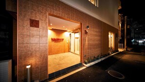 A hotel entrance with a tiled facade, a visible door, and a small outdoor area with plants. - Rakuten STAY Naha Yachimun Street (Naha)