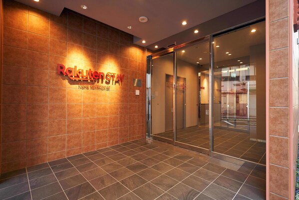 A hotel entrance with a sign reading "Rakuten Stay" and a glass door leading inside.