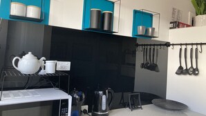 Una cocina moderna con microondas, hervidor y diversos utensilios en la pared.