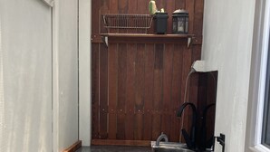 Un lavadero pequeño con lavadora, un lavabo y un estante de madera arriba.