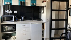 Una kitchenette compacta equipada con microondas, tostadora, hervidor y un refrigerador pequeño.