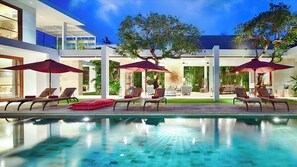 A modern pool area with lounge chairs and umbrellas, surrounded by lush greenery and a clear blue sky. - Casa Brio (Seminyak)