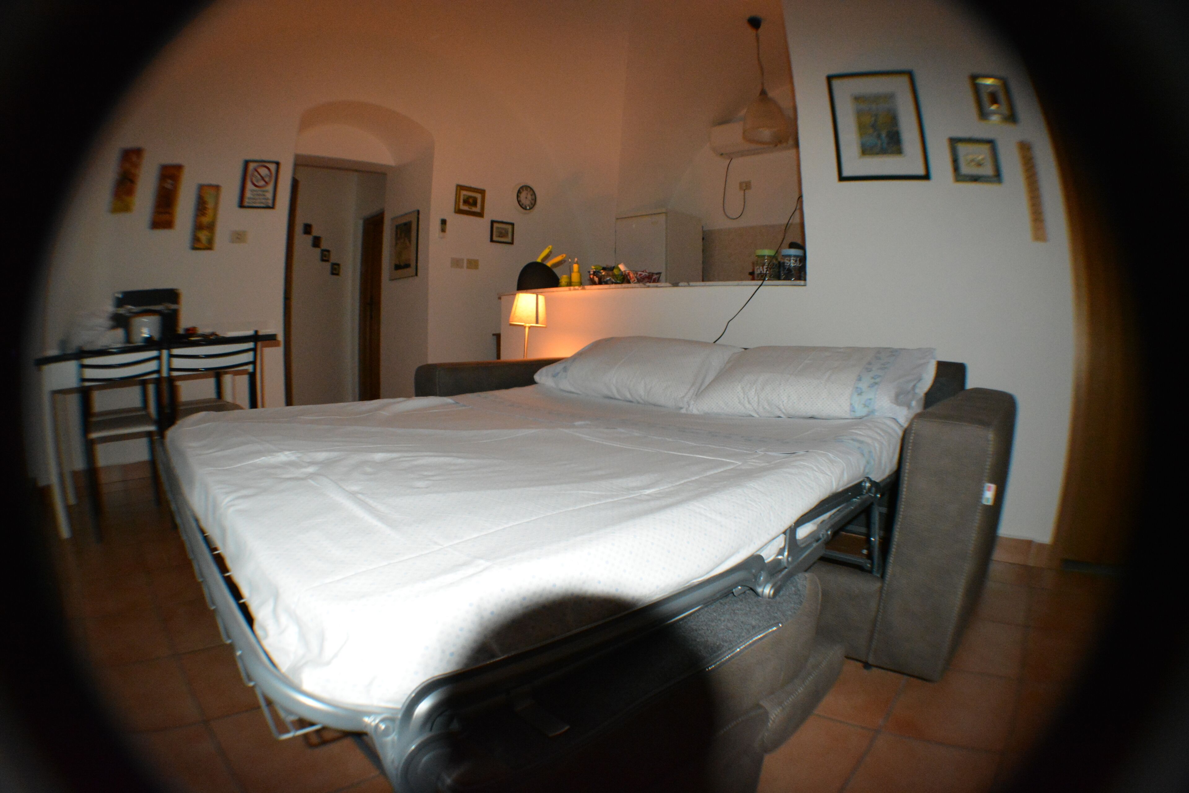 A bed with a metal frame, a bedside table with a lamp, and a chair.