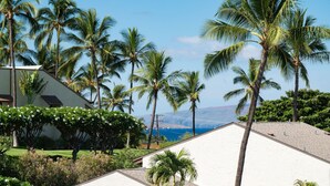 Un resort con edificios blancos, palmeras y vista al océano.