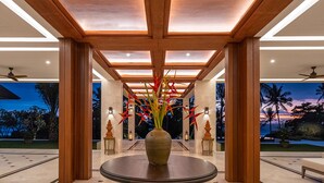 Un hall con una mesa redonda, pilares de madera y vistas al exterior al atardecer.