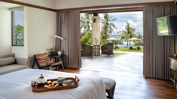 Habitación de hotel con cama, bandeja de té y aperitivos, televisor y vistas al exterior.