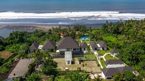 Un resort con varias construcciones tipo bungalow, una piscina y vista al océano.