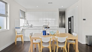 A modern kitchen with white cabinets, a wooden dining table, and chairs.