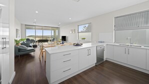 A modern kitchen with white cabinetry, a large island, and a view to the outdoors.