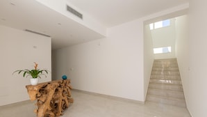Een ruim, modern interieur met een houten console tafel, een potplant en een trap naar een hoger niveau.